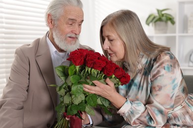 Photo of Cute couple with bouquet of red roses at home