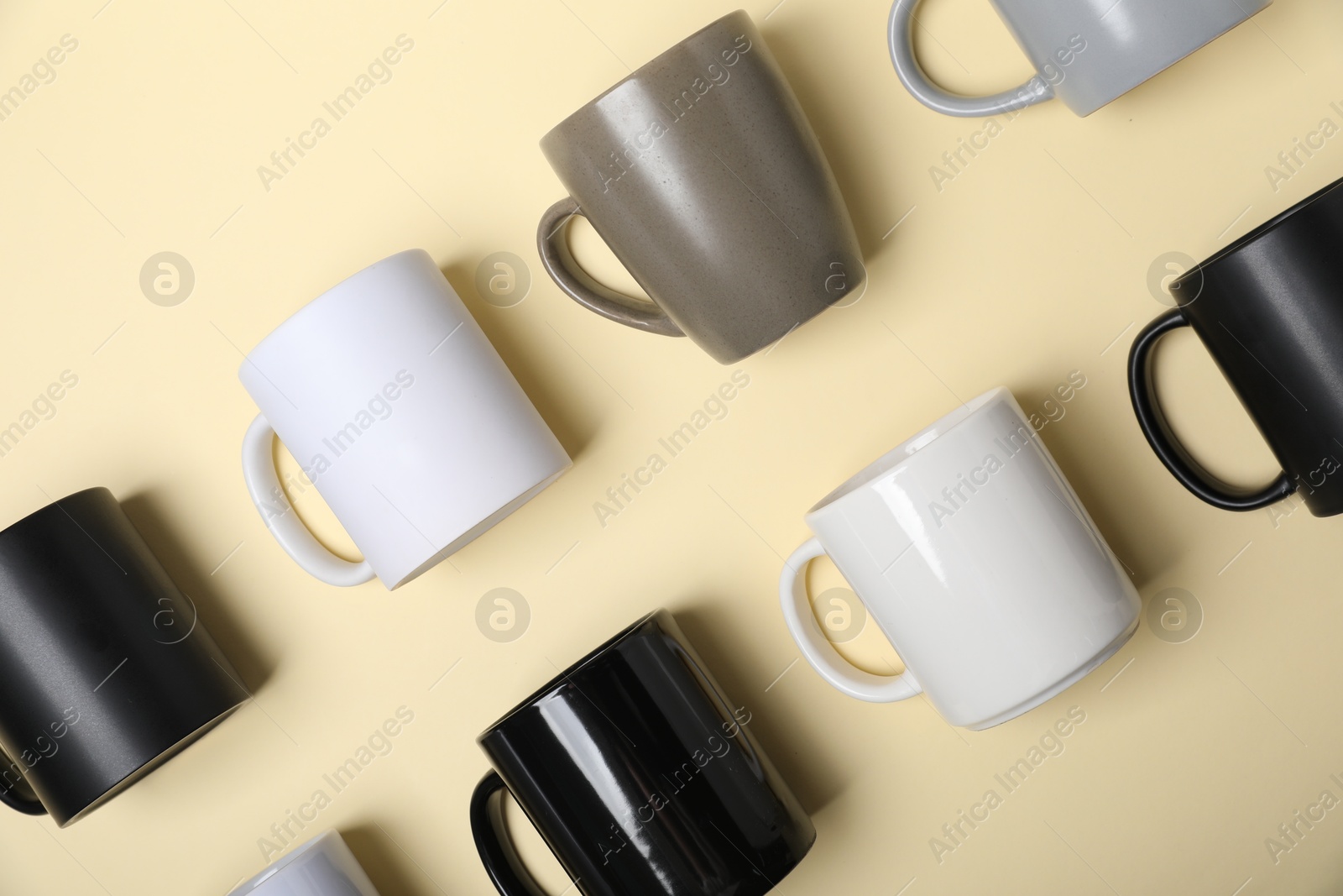 Many different cups on pale yellow background, flat lay Photo of Many different cups on pale yellow background, flat lay