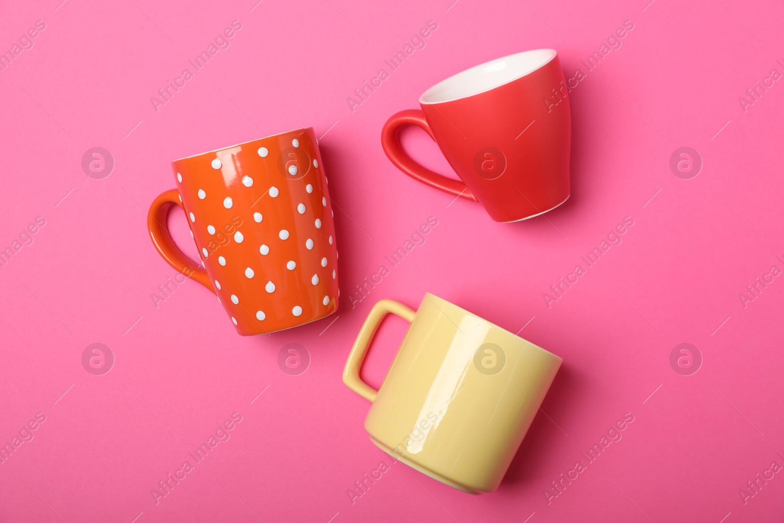 Many colorful cups on pink background, flat lay Photo of Many colorful cups on pink background, flat lay