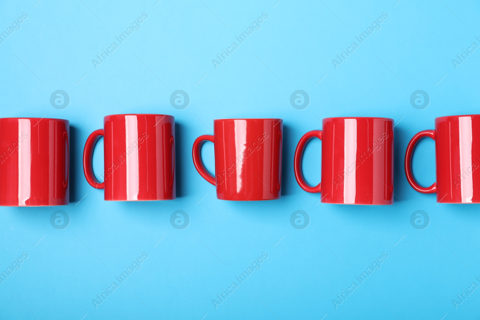 Many colorful cups on light blue background, flat lay Photo of Many colorful cups on light blue background, flat lay