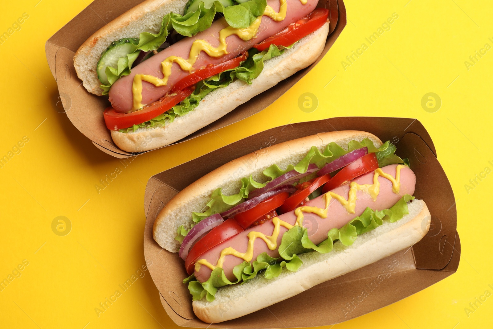 Tasty hot dogs on yellow background, flat lay Photo of Tasty hot dogs on yellow background, flat lay