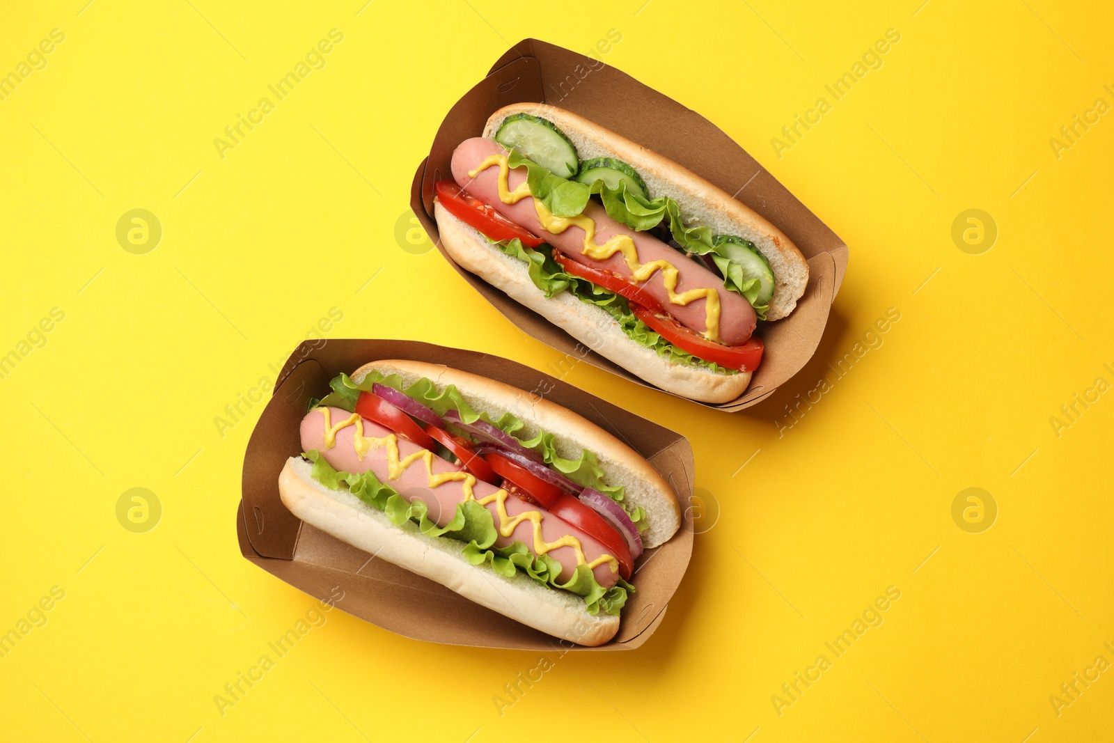 Tasty hot dogs on yellow background, flat lay Photo of Tasty hot dogs on yellow background, flat lay
