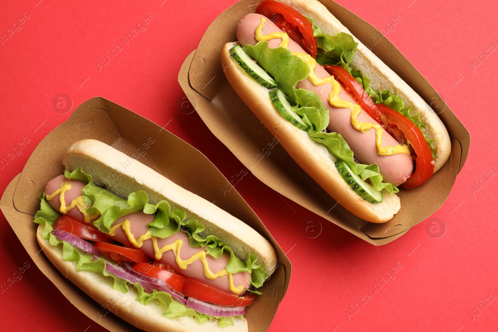 Tasty hot dogs on red background, flat lay Photo of Tasty hot dogs on red background, flat lay