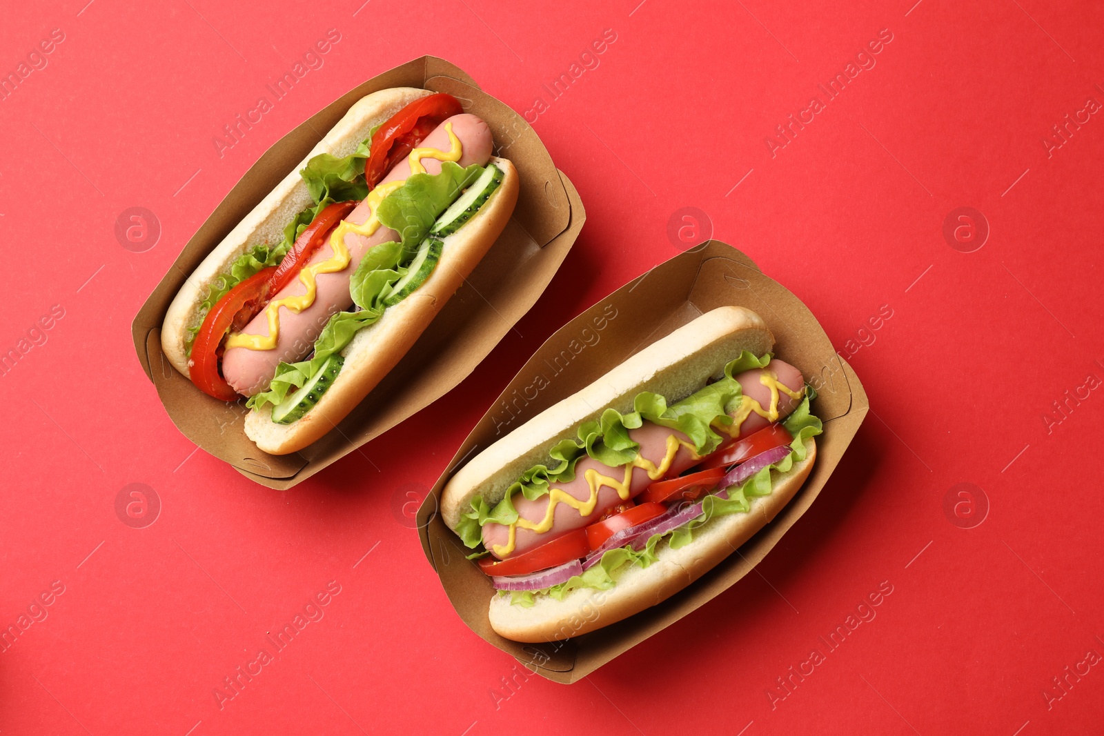 Tasty hot dogs on red background, flat lay Photo of Tasty hot dogs on red background, flat lay