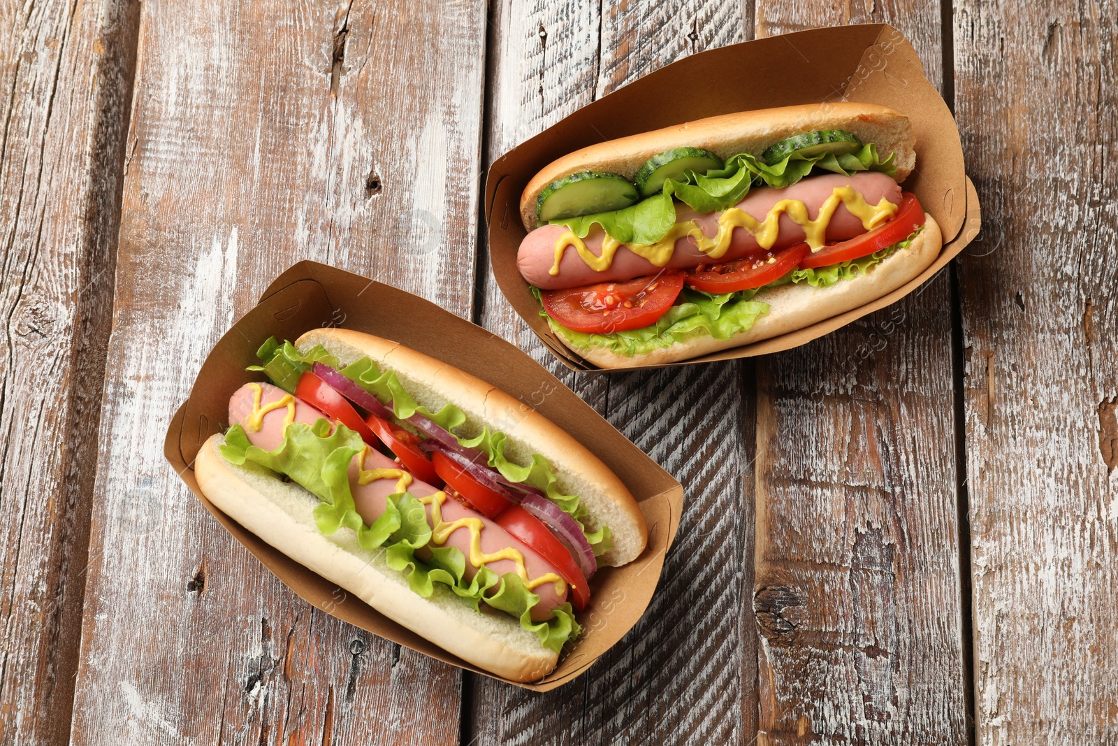 Tasty hot dogs on wooden table, flat lay Photo of Tasty hot dogs on wooden table, flat lay