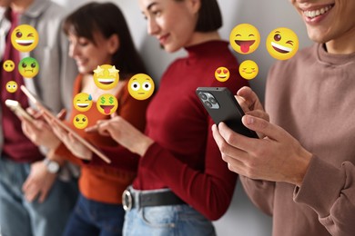 Image of Social media. Group of young people using different gadgets, closeup. Different emojis near them