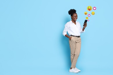 Image of Social media. Happy woman using mobile phone on light blue background. Different notification signs and emojis near gadget