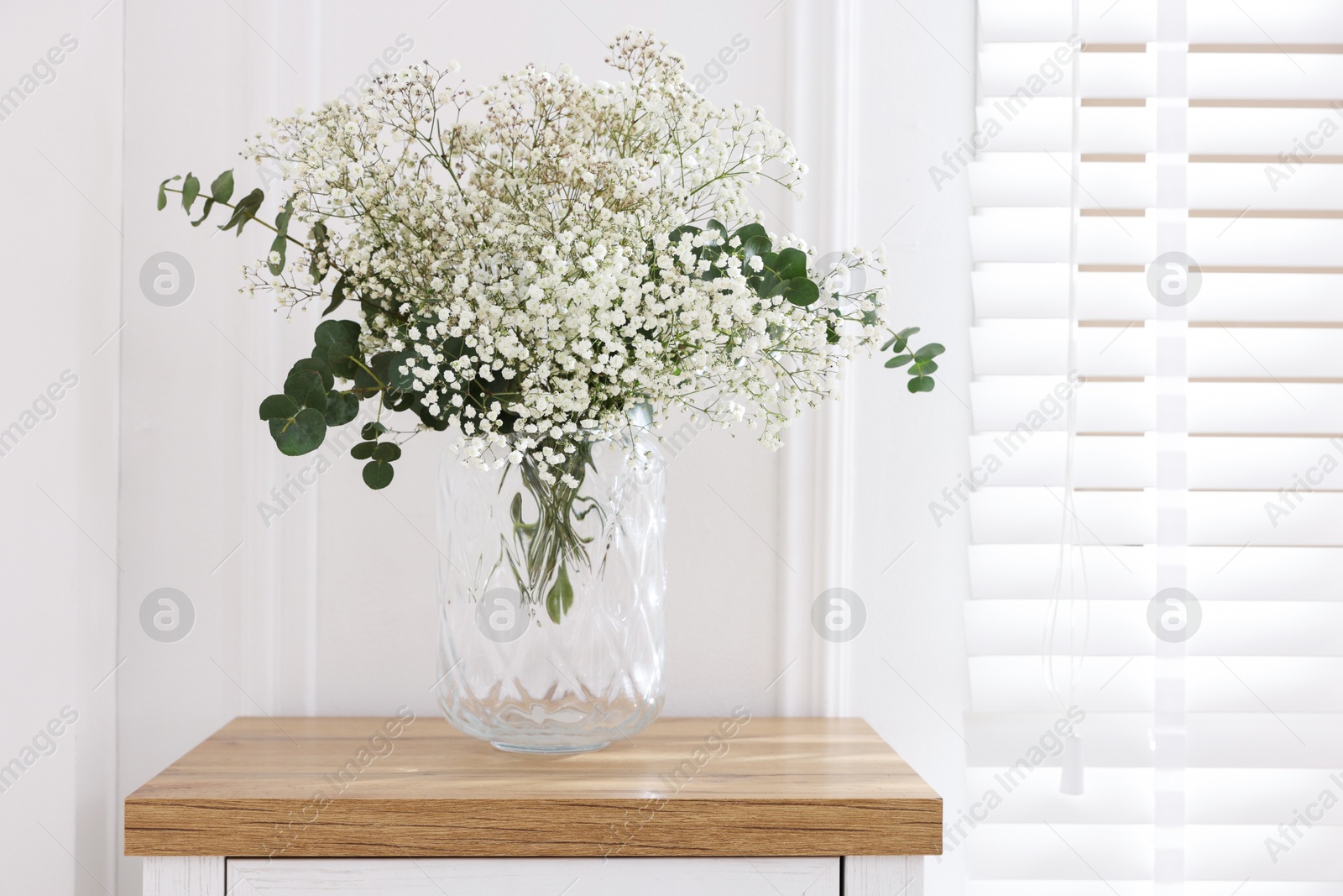 Beautiful gypsophila flowers and eucalyptus branches in vase on table at home. Space for text Photo of Beautiful gypsophila flowers and eucalyptus branches in vase on table at home. Space for text