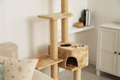 Photo of Stylish cat tree, chest of drawers and sofa in living room