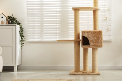 Photo of Stylish cat tree and chest of drawers in living room