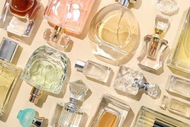 Photo of Bottles of various perfumes on beige background, flat lay