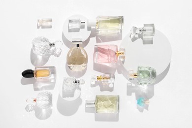 Photo of Different luxury perfumes on white background, flat lay