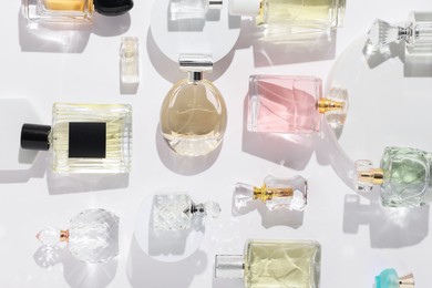 Photo of Different luxury perfumes on white background, flat lay