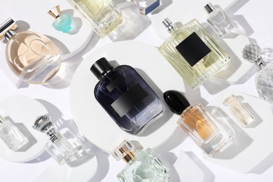 Photo of Different luxury perfumes on white background, flat lay