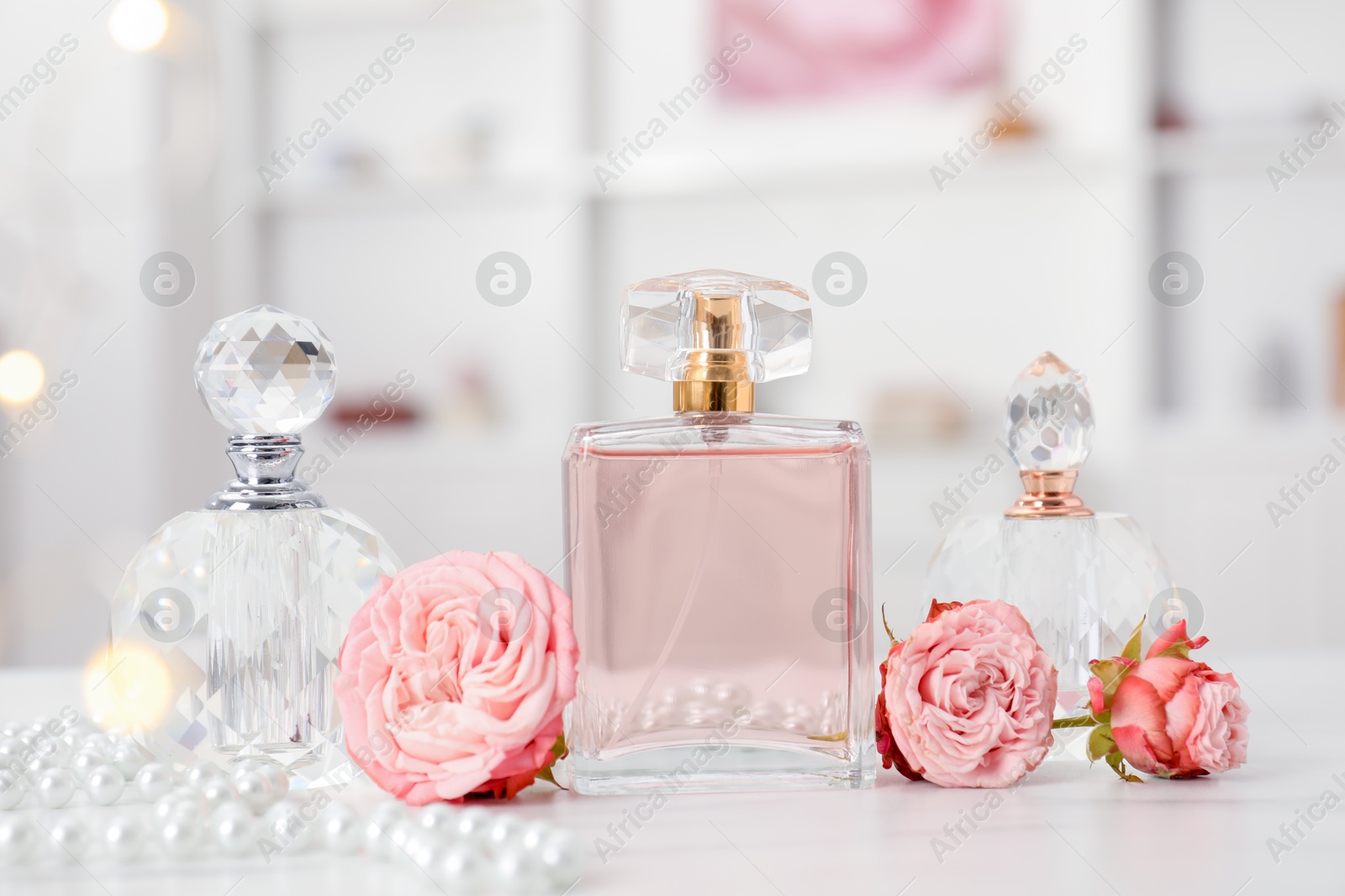 Bottles of perfume and beautiful flowers on white table Photo of Bottles of perfume and beautiful flowers on white table