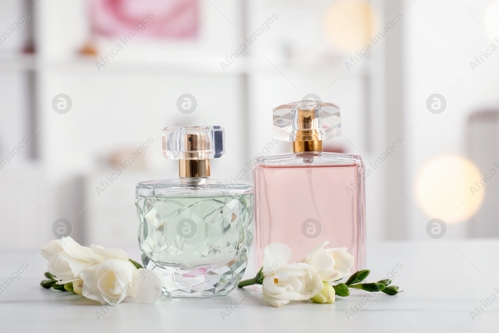 Bottles of perfume and beautiful flowers on white table Photo of Bottles of perfume and beautiful flowers on white table