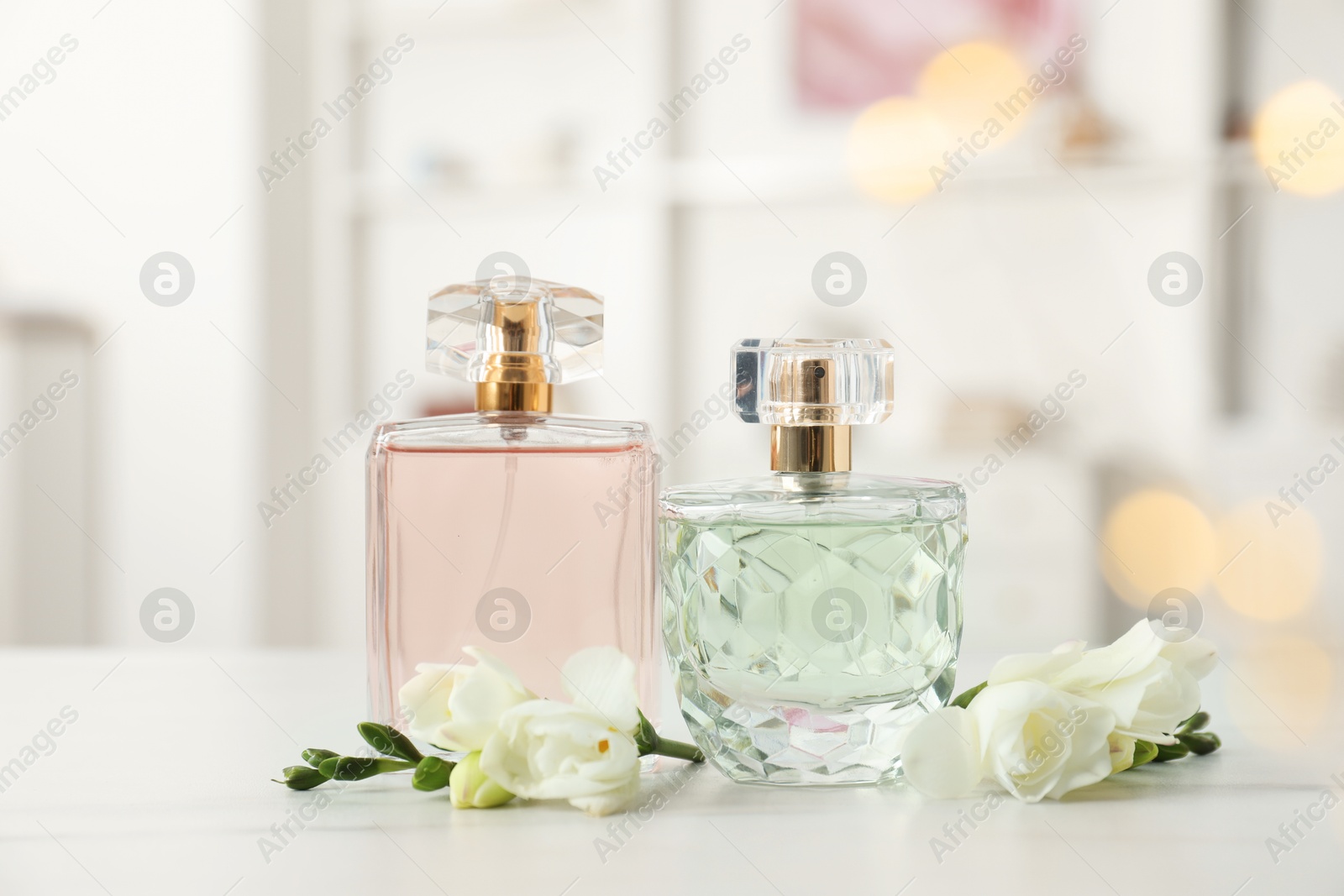 Bottles of perfume and beautiful flowers on white table Photo of Bottles of perfume and beautiful flowers on white table
