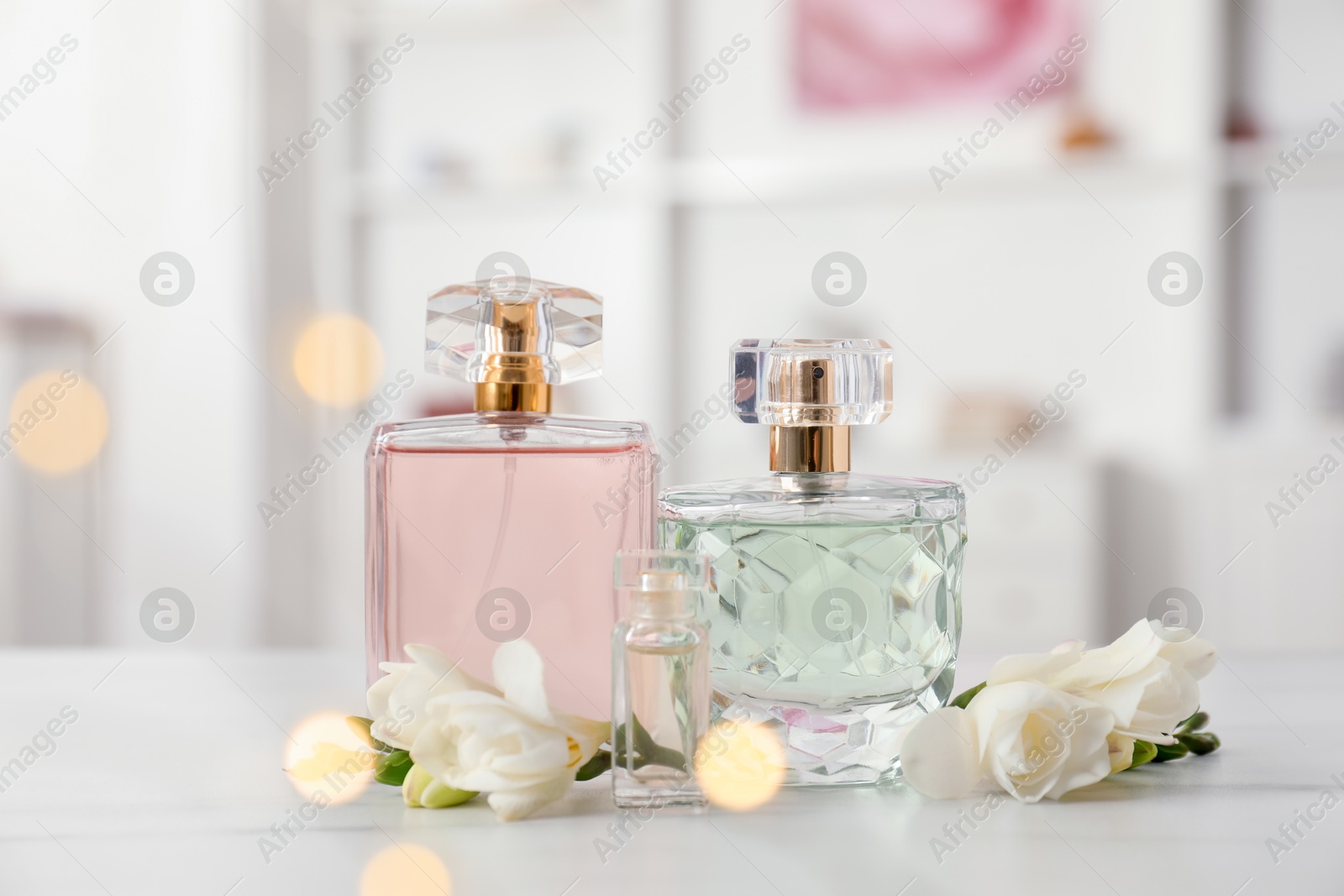 Bottles of perfume and beautiful flowers on white table Photo of Bottles of perfume and beautiful flowers on white table