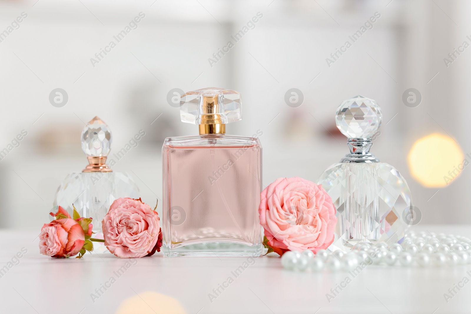 Bottles of perfume and beautiful flowers on white table Photo of Bottles of perfume and beautiful flowers on white table