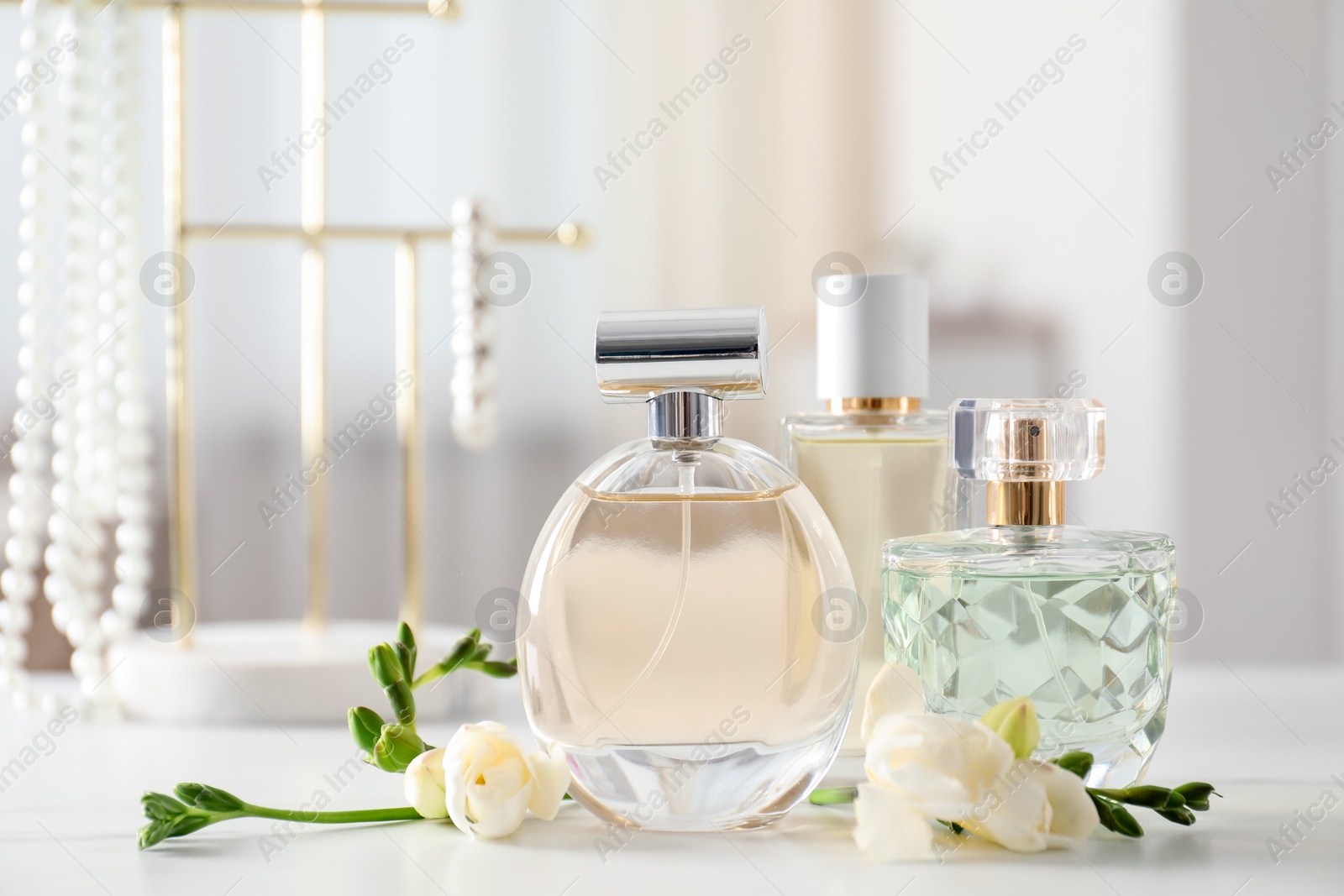 Bottles of perfume and beautiful flowers on white table Photo of Bottles of perfume and beautiful flowers on white table