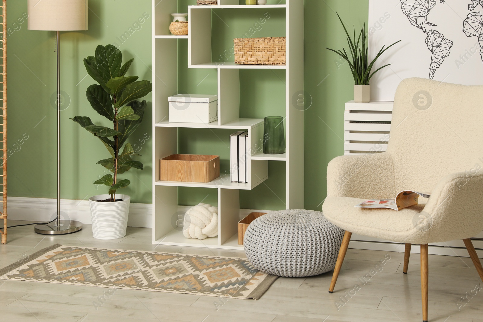 Stylish living room with comfortable armchair and wooden shelving unit. Interior design Photo of Stylish living room with comfortable armchair and wooden shelving unit. Interior design