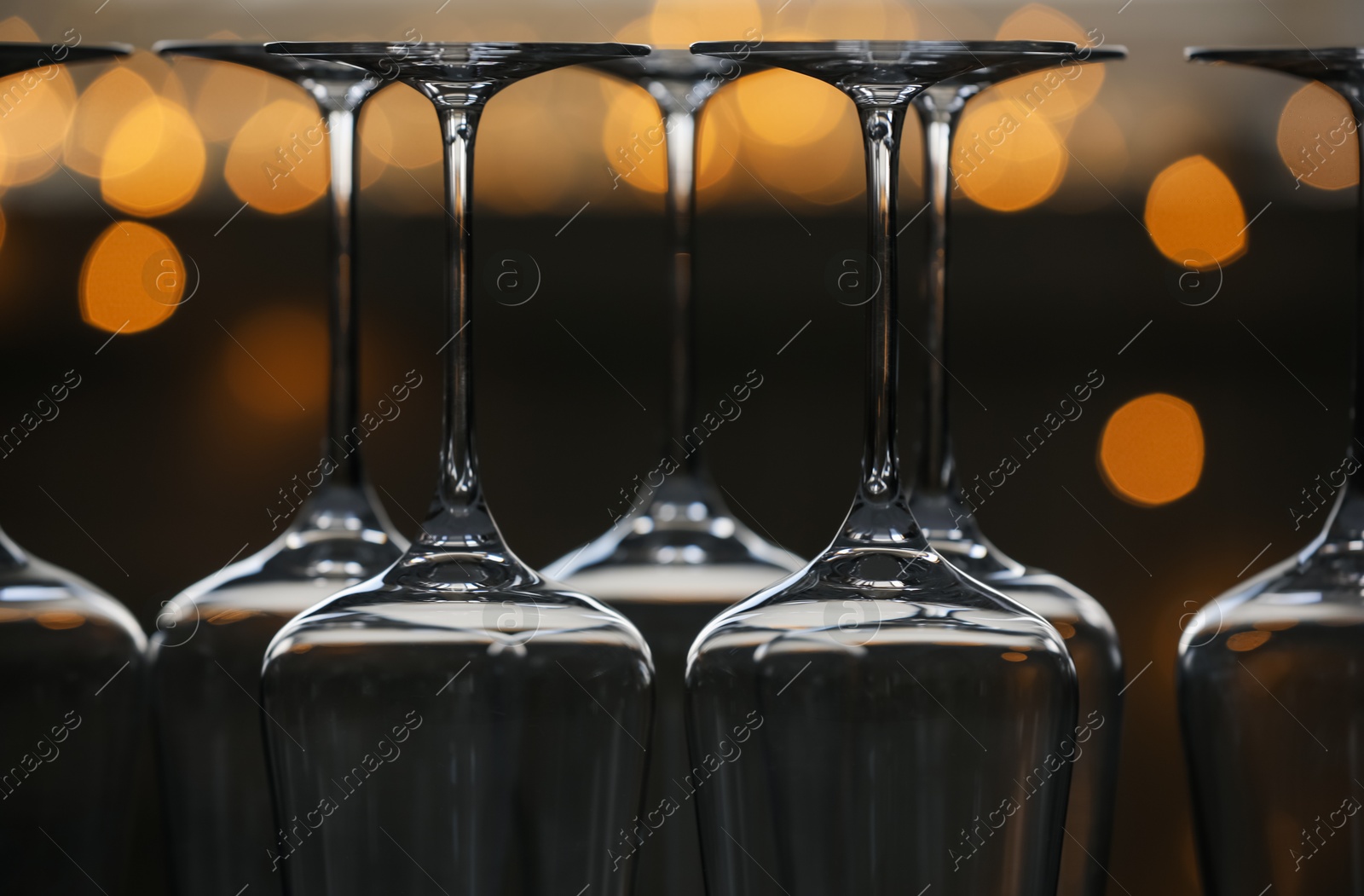 Upturned empty clean glasses on blurred background, closeup. Bokeh effect Photo of Upturned empty clean glasses on blurred background, closeup. Bokeh effect