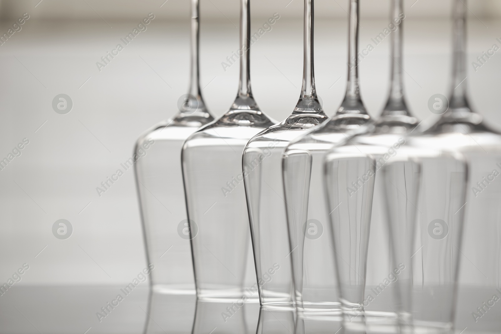 Upturned empty clean glasses on mirror surface against blurred background, closeup. Space for text Photo of Upturned empty clean glasses on mirror surface against blurred background, closeup. Space for text