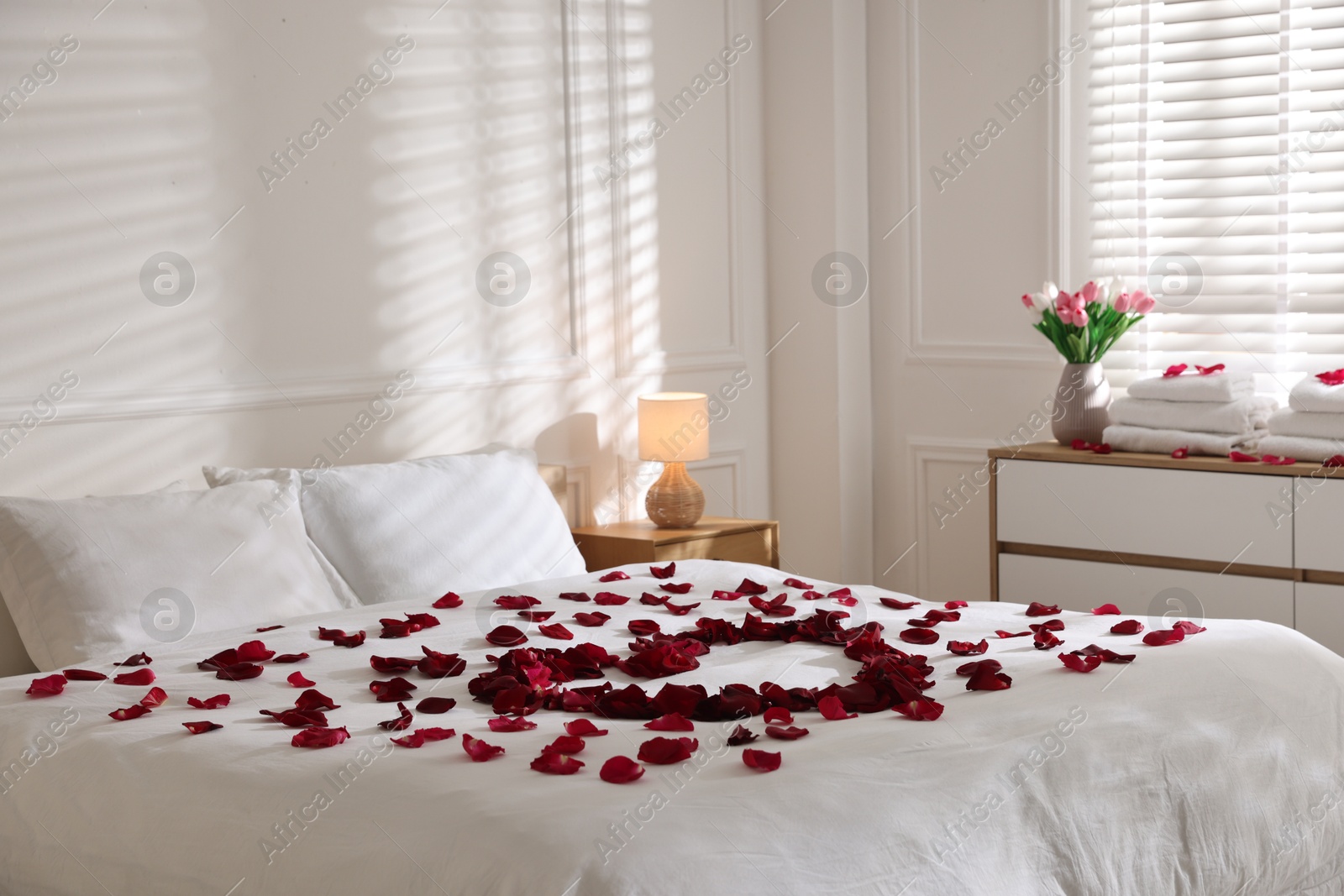 Heart made with rose petals on bed indoors Photo of Heart made with rose petals on bed indoors