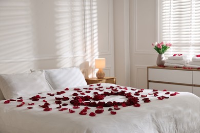 Photo of Heart made with rose petals on bed indoors