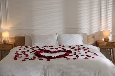 Photo of Heart made with rose petals on bed indoors
