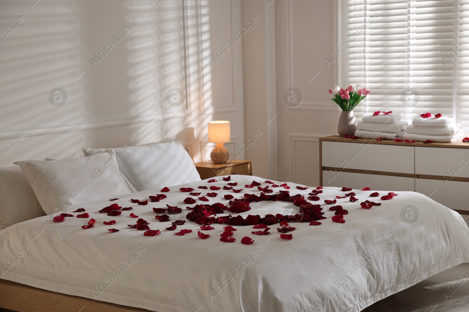 Heart made with rose petals on bed indoors Photo of Heart made with rose petals on bed indoors