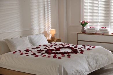 Photo of Heart made with rose petals on bed indoors