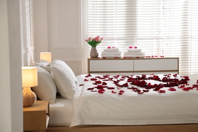 Photo of Heart made with rose petals on bed indoors