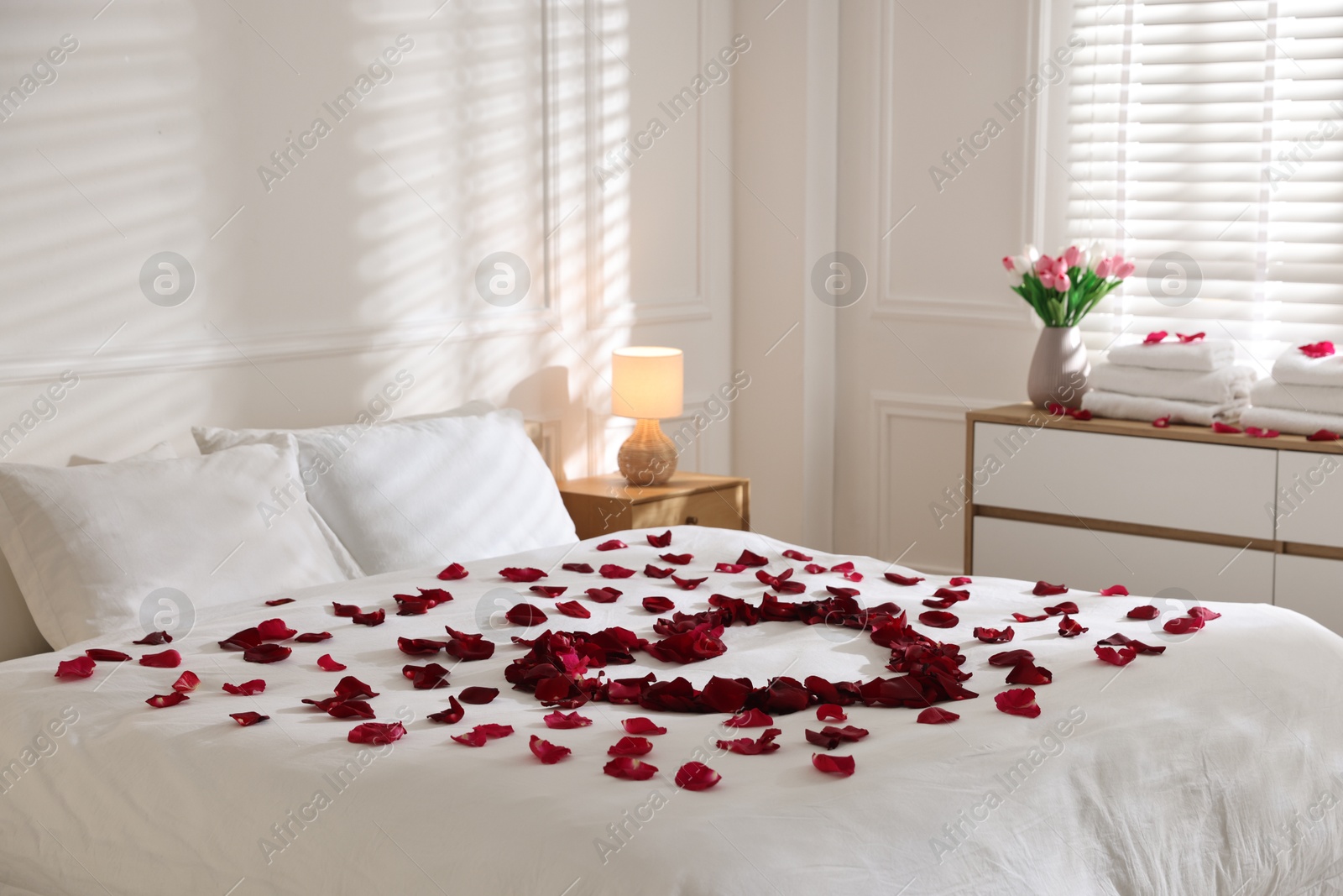 Heart made with rose petals on bed indoors Photo of Heart made with rose petals on bed indoors