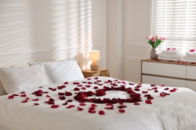 Photo of Heart made with rose petals on bed indoors