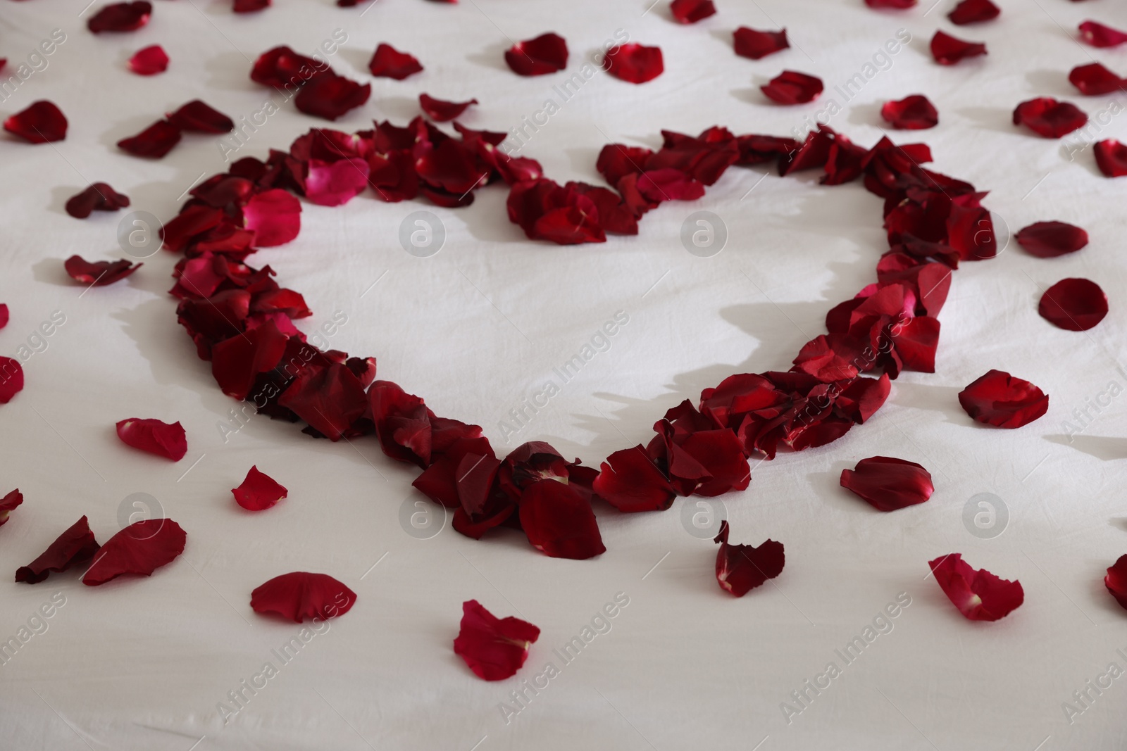 Heart made with rose petals on bed, closeup Photo of Heart made with rose petals on bed, closeup