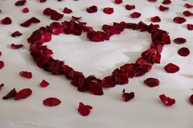 Photo of Heart made with rose petals on bed, closeup