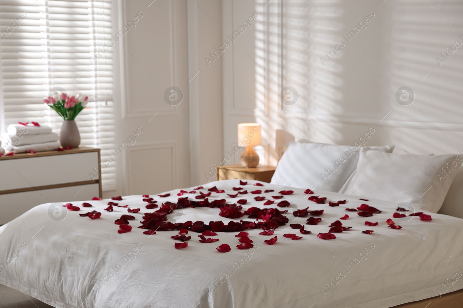 Heart made with rose petals on bed indoors Photo of Heart made with rose petals on bed indoors