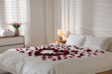 Photo of Heart made with rose petals on bed indoors