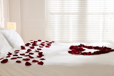 Photo of Heart made with rose petals on bed indoors