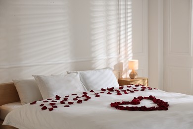 Photo of Heart made with rose petals on bed indoors
