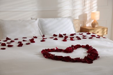 Photo of Heart made with rose petals on bed indoors