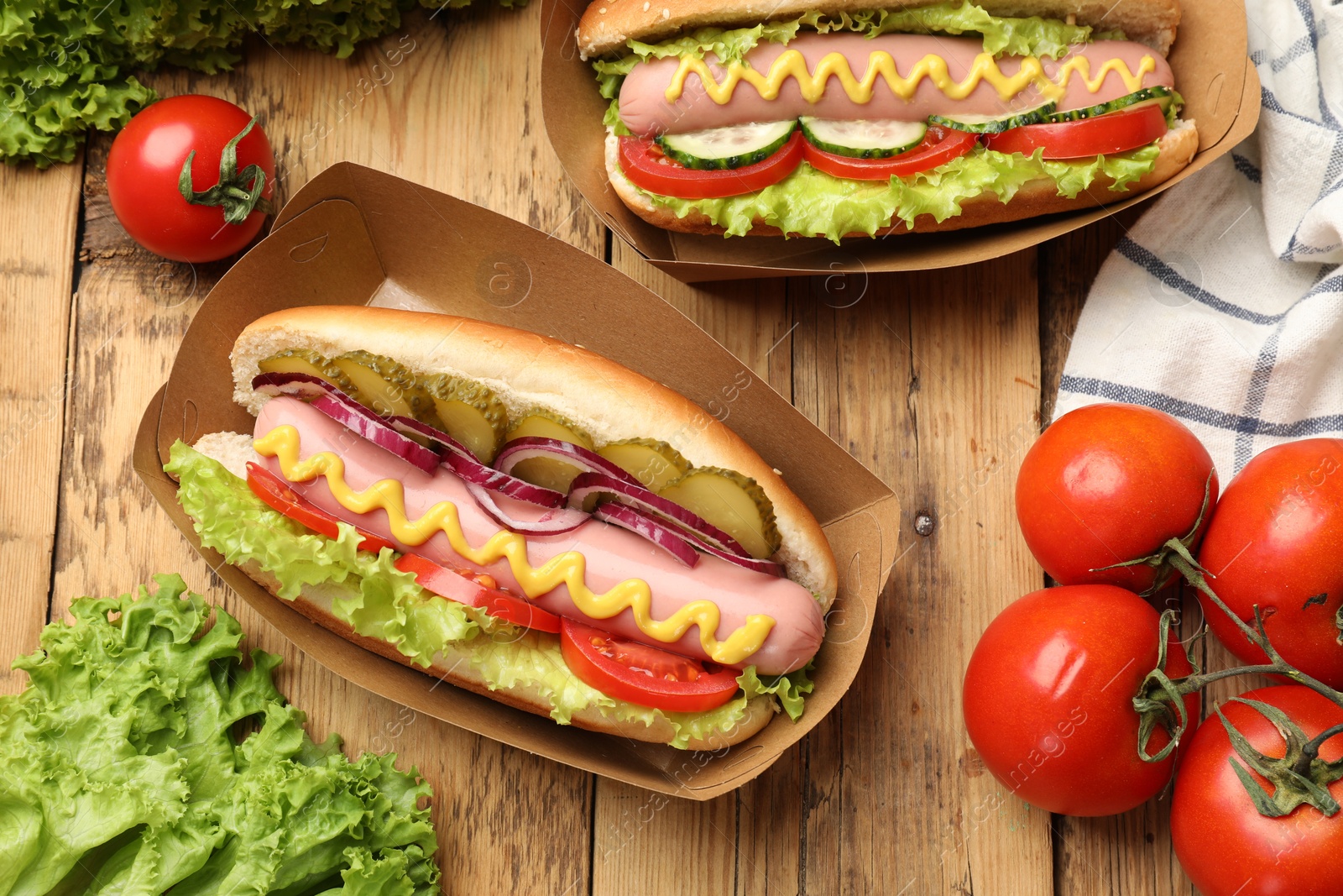 Tasty hot dogs with vegetables on wooden table, flat lay Photo of Tasty hot dogs with vegetables on wooden table, flat lay