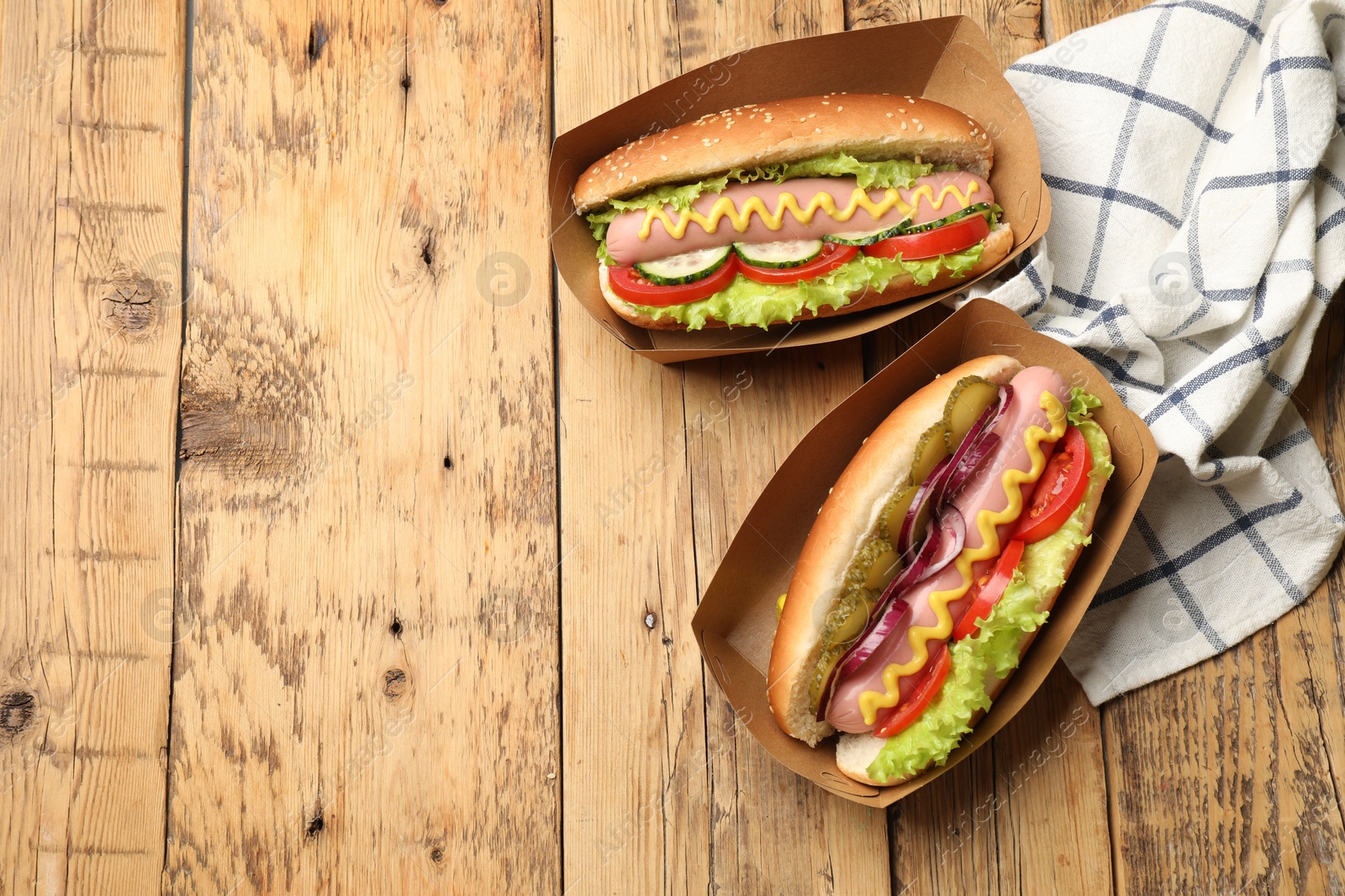 Tasty hot dogs with vegetables on wooden table, flat lay. Space for text Photo of Tasty hot dogs with vegetables on wooden table, flat lay. Space for text