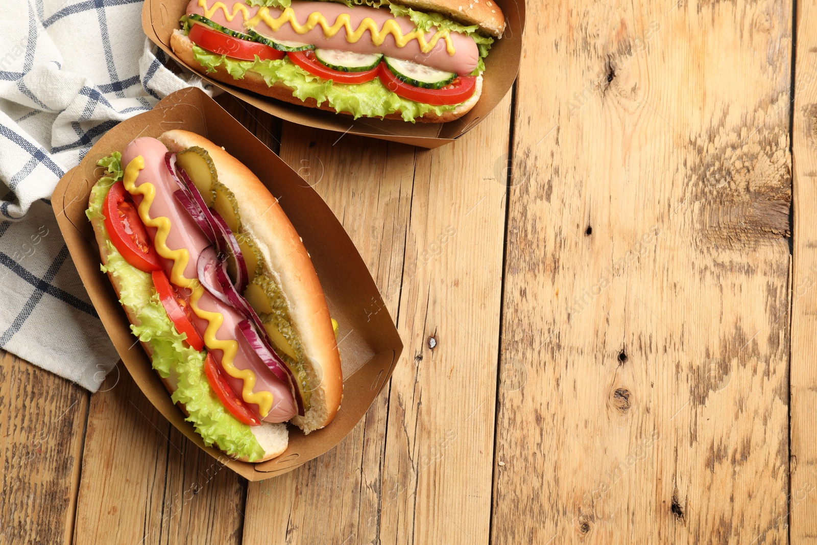 Tasty hot dogs with vegetables on wooden table, flat lay. Space for text Photo of Tasty hot dogs with vegetables on wooden table, flat lay. Space for text