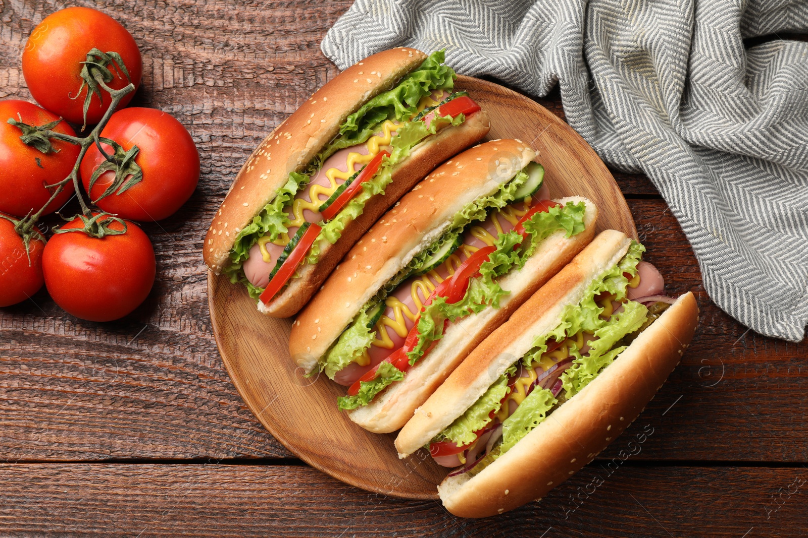 Tasty hot dogs with vegetables on wooden table, flat lay Photo of Tasty hot dogs with vegetables on wooden table, flat lay