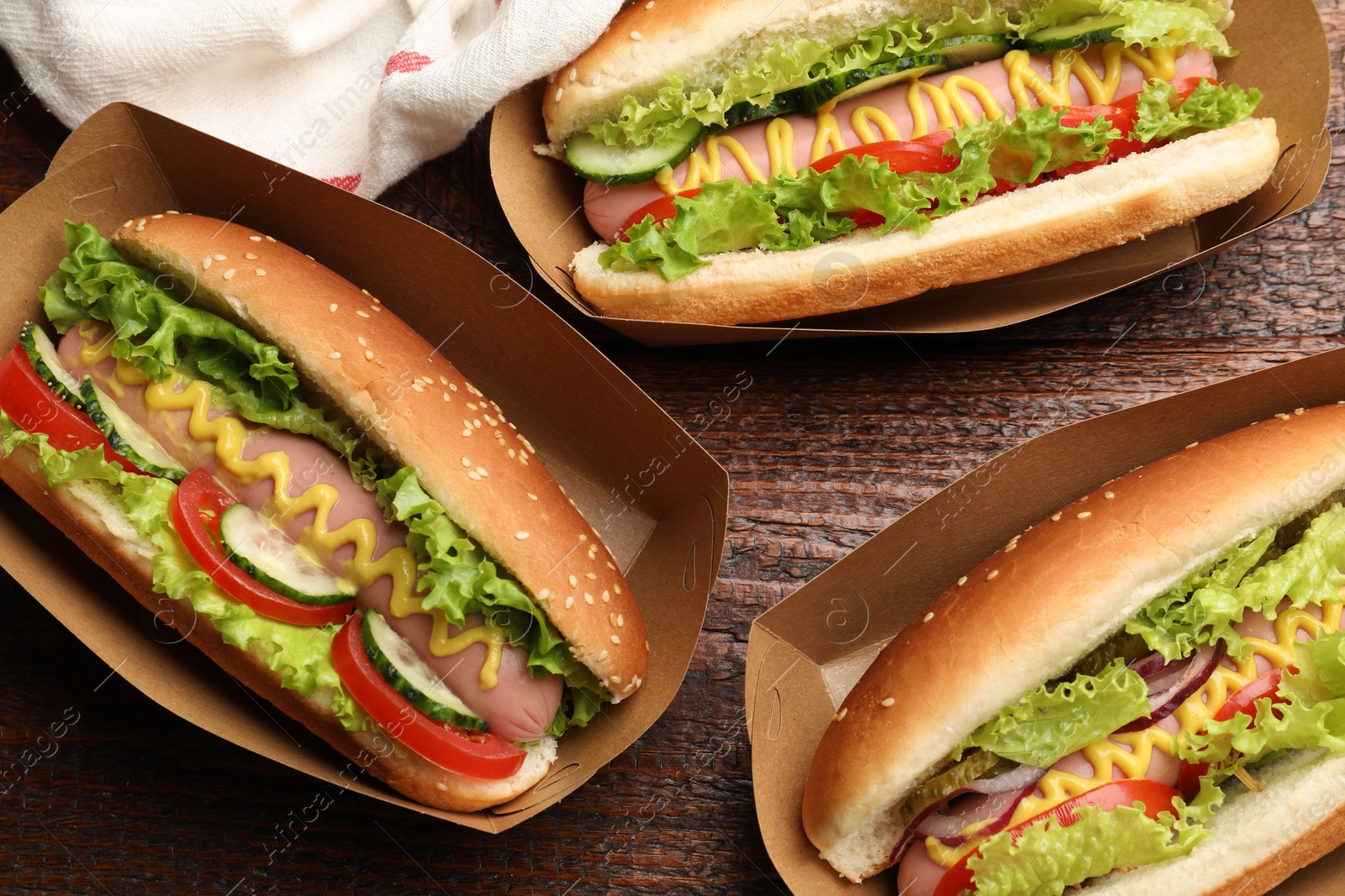Tasty hot dogs with vegetables on wooden table, flat lay Photo of Tasty hot dogs with vegetables on wooden table, flat lay