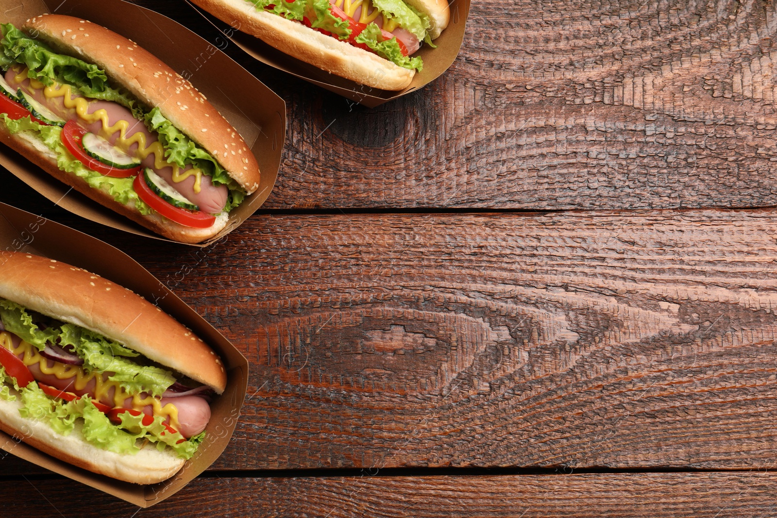 Tasty hot dogs with vegetables on wooden table, flat lay. Space for text Photo of Tasty hot dogs with vegetables on wooden table, flat lay. Space for text