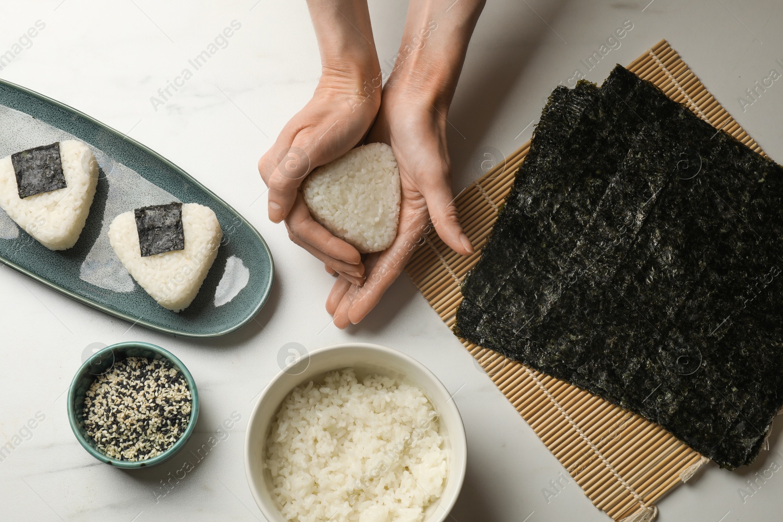 Woman making tasty onigiri (Japanese rice balls) at white table, top view Photo of Woman making tasty onigiri (Japanese rice balls) at white table, top view