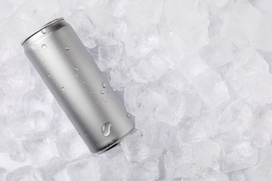 Photo of Refreshing drink in can on ice cubes, top view. Space for text